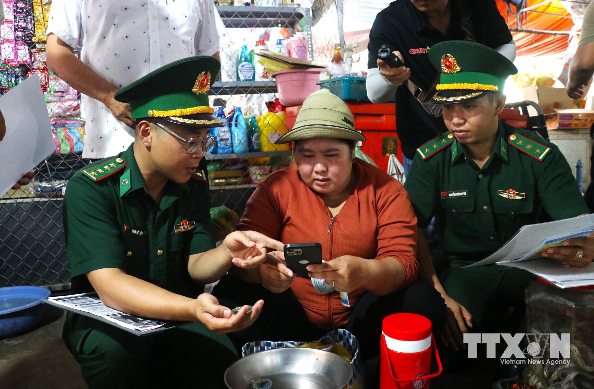 Đại úy Phạm Việt Tiến trò chuyện, tuyên truyền pháp luật cho người dân tại khu vực chợ Tho Mo, đưa những quy định về biên giới, phòng, chống tội phạm đến gần hơn với đời sống. (Ảnh: Bùi Giang/TTXVN)